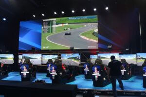 Image of competitors playing auto racing simulation game at a tournament